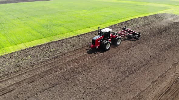 Red Harvester Drives Across Field and Plows Earth