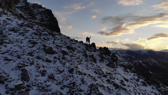 Aerial View Silhouettes of Two Tourists Man and Woman Stand High in the Mountains Against the