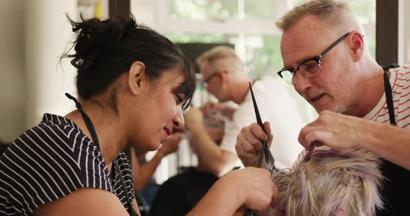 Close up view woman having her hair styled by two hairdressers