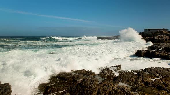 Wave crashes and runs onto rocks of rocky coastline; rough ocean