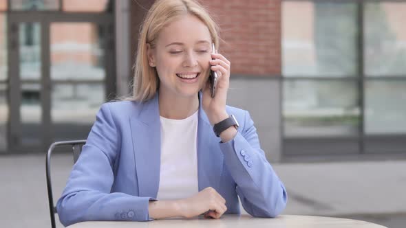 Young Businesswoman Talking on Phone Sitting Outdoor