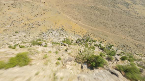 Fast FPV drone flying down dry mountain hill in national park