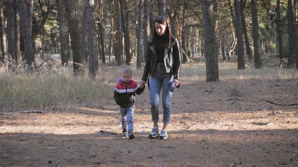 Young Mother Walking with a Little Son in Autumn Forest