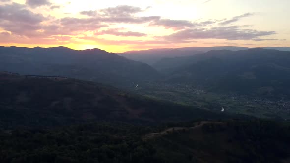Aerial View Flying Over Green Hills At Sunset