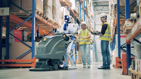 Two Workers Restart Stopped Warehouse Robot with Vacuum Cleaner
