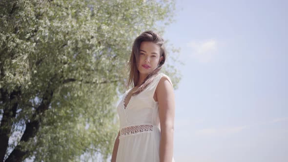 Portrait of Lovely Young Girl with Long Brunette Hair Wearing a Long White Summer Fashion Dress