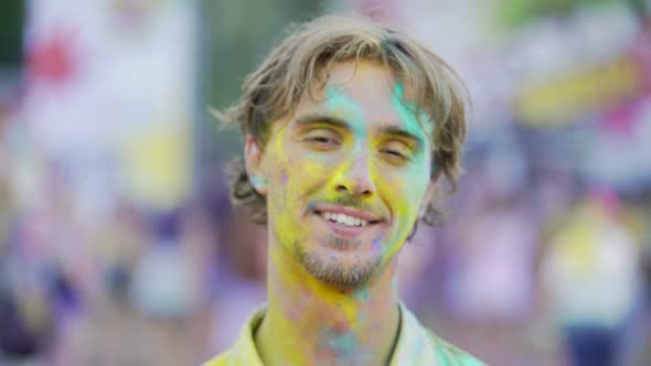 Cheerful Young Man Covered in Colorful Dyes Enjoying Atmosphere at Festival