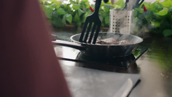 Close-up View of Frying Pan with Meat Pieces and Male Hand Cooking Meal