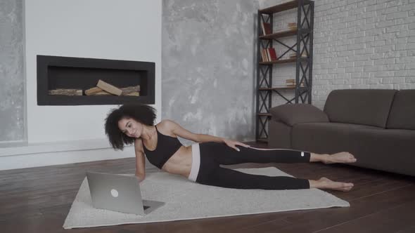 Young Multiracial Woman Female Doing Her Exercises at Home Using a Laptop To Repeat Moves From Video