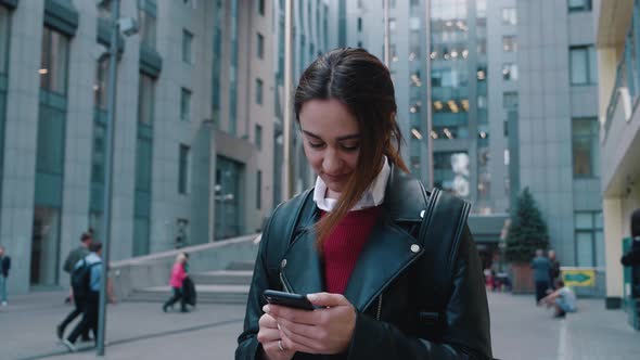 A Young Woman Stands With A Phone On The Background Of A Business Center