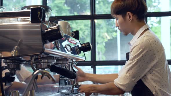 Close up Asian barista at work during making coffee in coffee cafe.