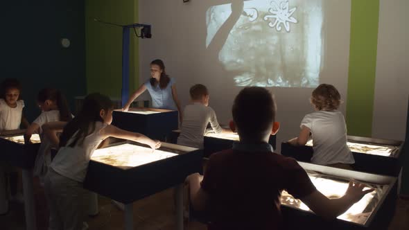 Woman Teaching Sand Animation Class for Children