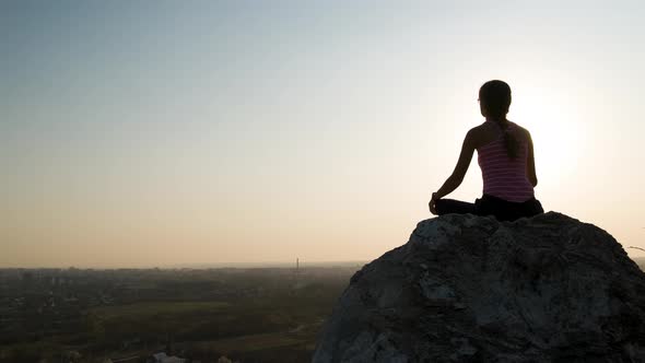 Young Relaxed Woman Sitting Outdoors on a Big Stone Enjoying Warm Summer Day