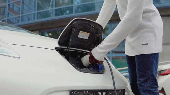 A Young African American Man Connects an Electric Car to the Charger