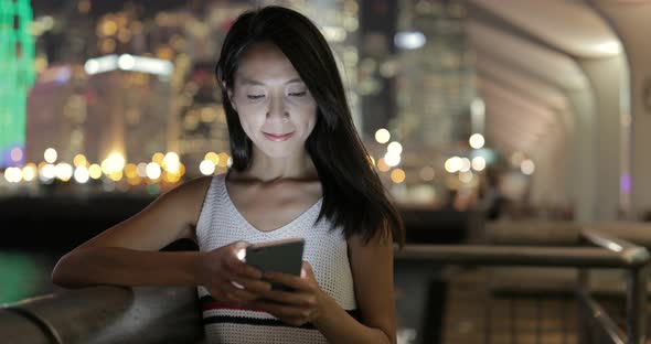 Woman looking at mobile phone in the city at night 