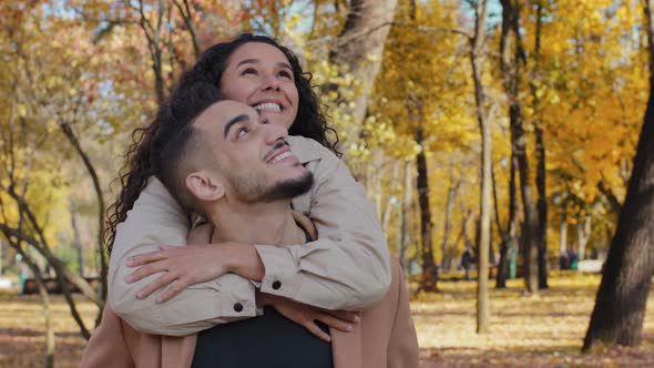 Close Up Hispanic Couple on Date in Autumn Park Happily Smiling Attractive Girl Hug Male By
