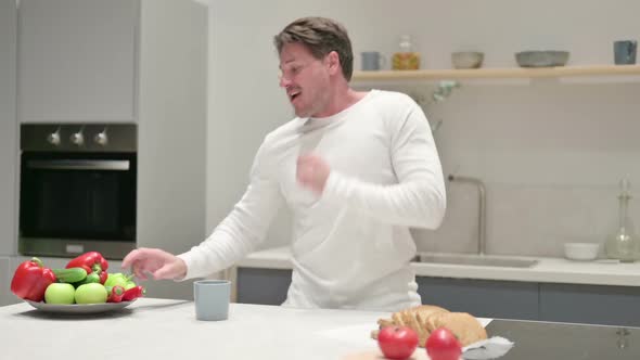 Happy Man Dancing While Drinking Coffee in Kitchen