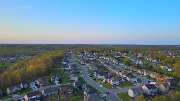 Aerial fly through of beautiful suburban neighborhood with blue skies at sunset