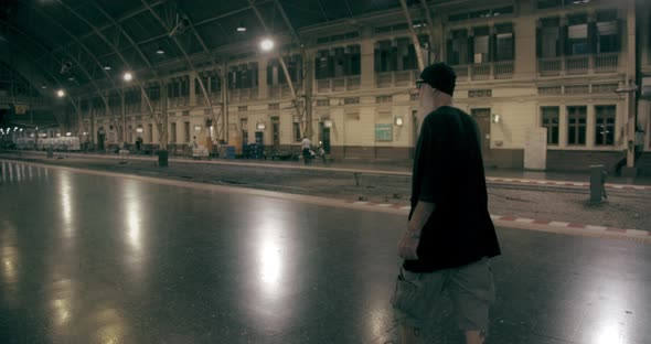 Panning Shot Of A Man Walking Along the Platform On A Train Station