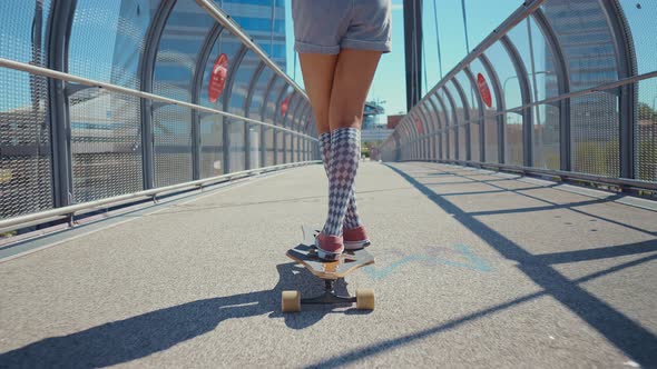 Beautiful young woman cruising around the city with her longboard.