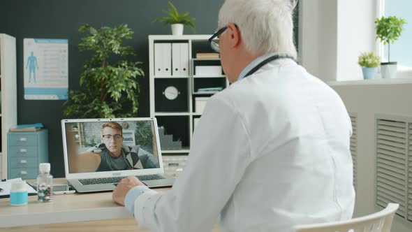 Medic Giving Advice To Unhealthy Person During Internet Consultation Using Computer in Hospital