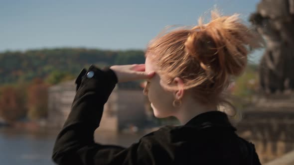 Woman Shielding Eyes From Sun As She View River From Charles Bridge