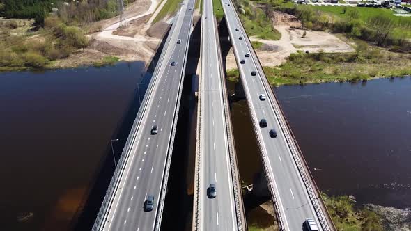 Vehicles driving over three highway bridges over river Neris in Kaunas, aerial tilt up reveal view