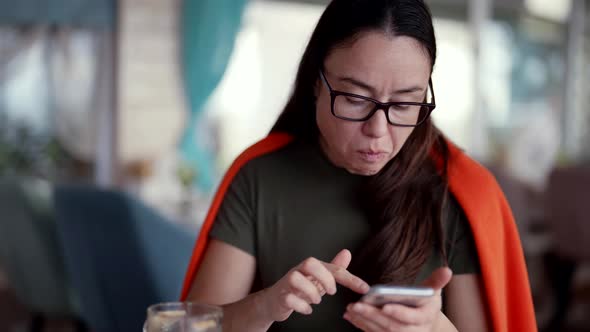 Woman with Smartphone is Eating and Drinking Coffee in Cafe in Daytime Internet Addiction