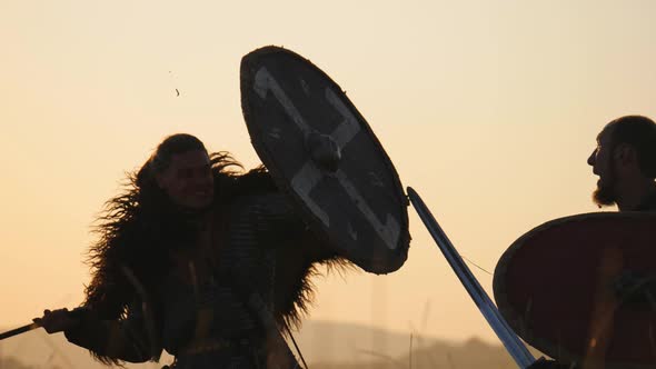 Silhouettes of Warriors Viking Are Fighting with Swords and Shields. Contre-jour
