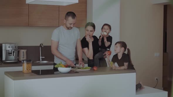 Happy Young Family with Mum, Dad with Two Daughters Cut Vegetables for Salads, and Treat Each Other