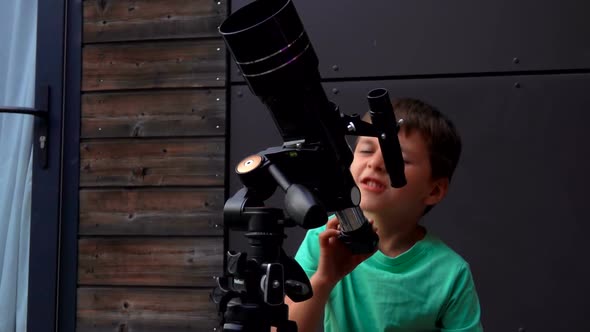 A Little Cute Boy in Green Tshirt is Setting Up a Telescope to Look at the Sky