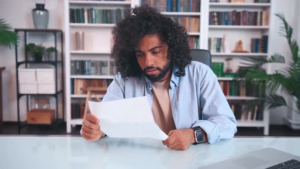 Overjoyed Successful Young Arabian Man Freelancer Enjoys Reading Paper Letter