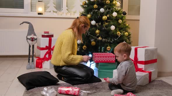 Happy Mother Having Fun and Playing Together with Her Son Near Christmas Tree at Home