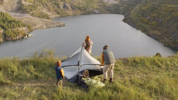 Family Setting Up Tent in Scenic Place