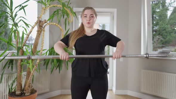 Confident Overweight Caucasian Sportswoman Lifting Barbell Bar Indoors