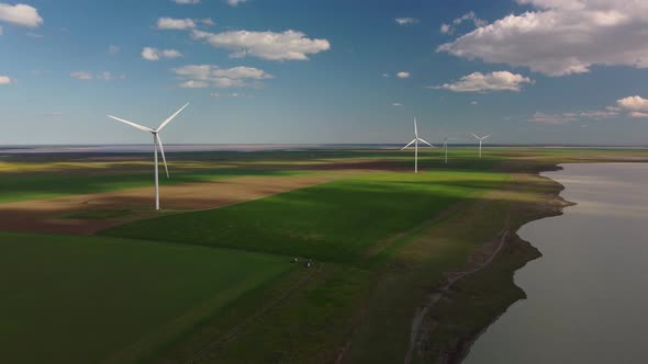 Aerial View of Wind Turbines and Agriculture Field Near the Sea at Sunset