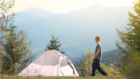Hiker Child Boy Resting Near a Tourist Tent at Mountain Campsite Enjoying View of Beautiful Summer