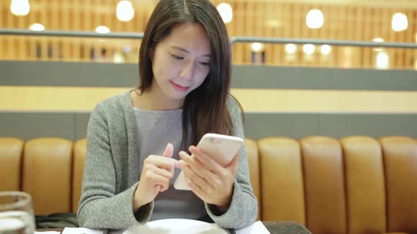 Woman working on mobile phone in restaurant