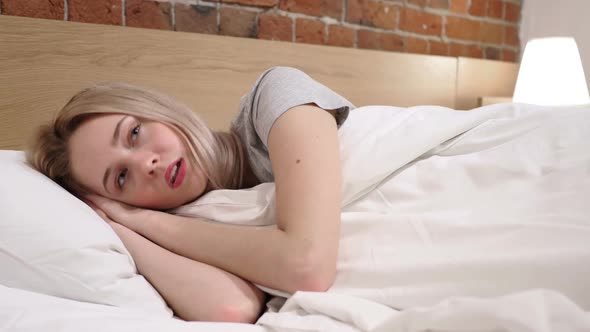 Upset Woman Lying in Bed on Side at Night