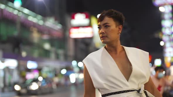 4K Confidence Asian lgbtq guy wearing woman clothes walking down city street at night