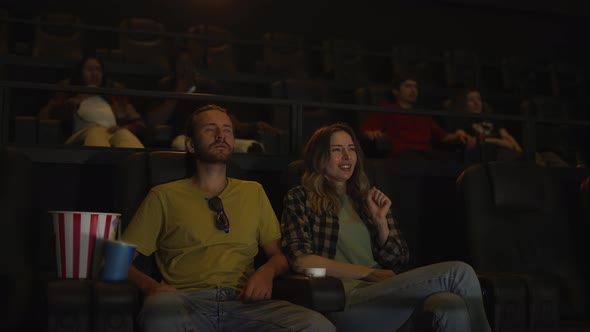 Beautiful Girl Looking Scary While Watching Film and Snuggling to Her Boyfriend Sitting Next to Her