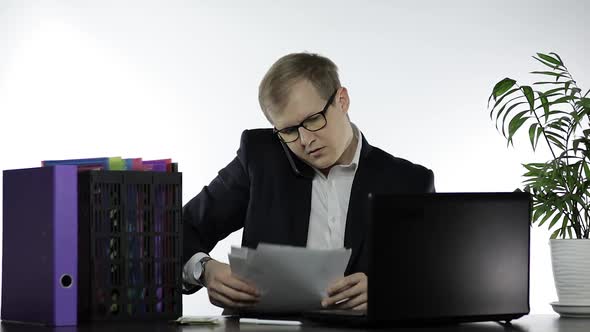 Businessman Working in Office. Talking Loudly on Telephone While Reading Papers