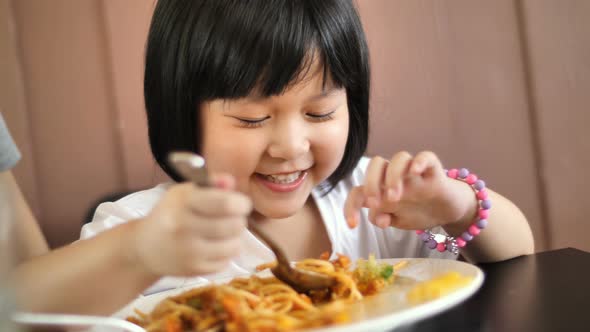 Happy Asian child eating delicious spaghetti.