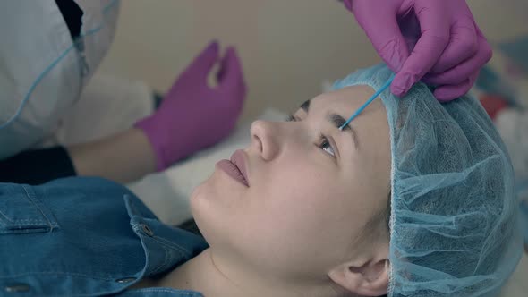 Client Lies on Couch During Cosmetologist Examining Brows