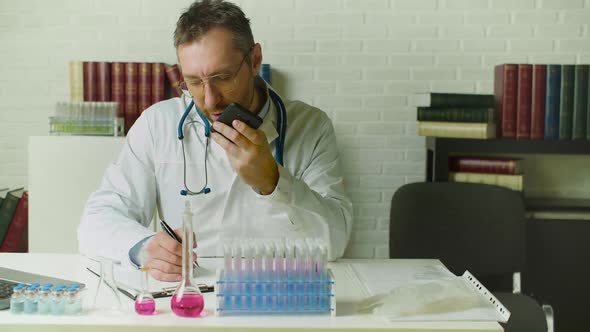 Dolly Shot of a Middleaged Doctor Records a Voice Message on His Phone