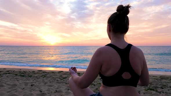 Young Woman Relaxing and Practicing Yoga on the Beach