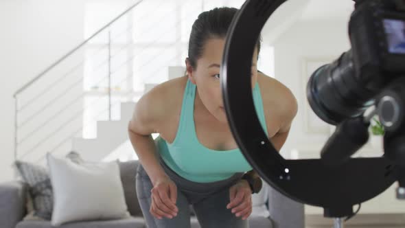 Happy asian woman preparing camera for making fitness vlog from home