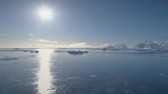 Aerial Flight Over Antarctica Ocean. Bright Sun.