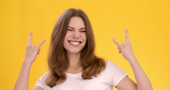 Studio Shot Young Cheerful Woman Showing Punk Horn Gesture Orange Background Slow Motion