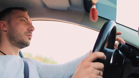 A Handsome Man is Driving with a Window Ajar